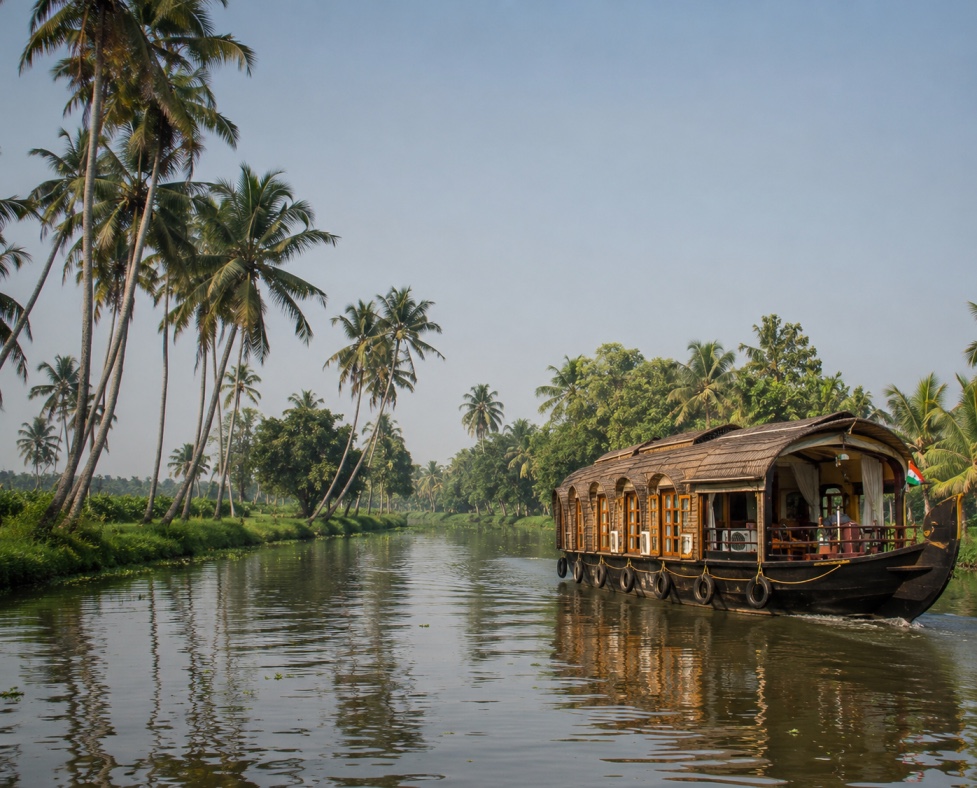 Traditional Kerala houseboat gliding along the Alleppey backwaters, framed by coconut palms