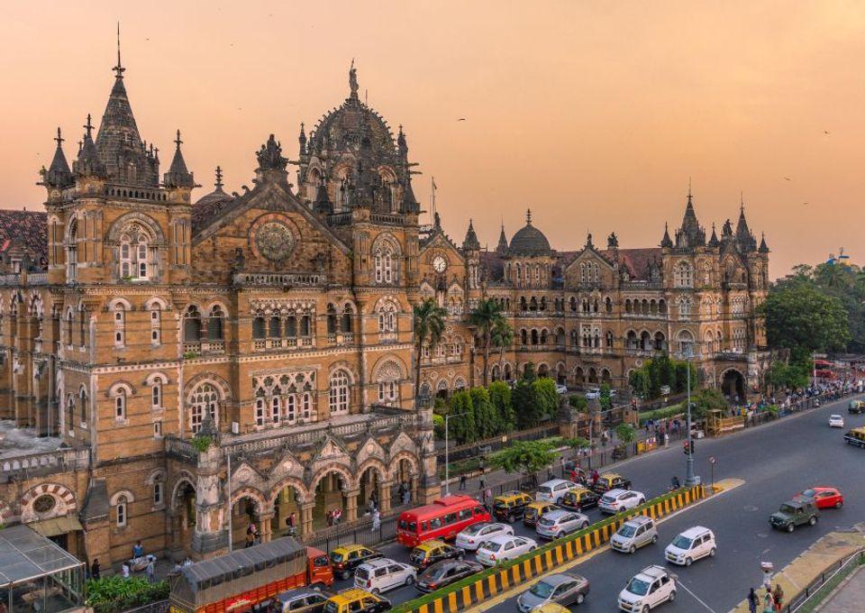 Chhatrapati Shivaji Maharaj Terminus in Mumbai at dusk, with traffic streaming past its Gothic facade