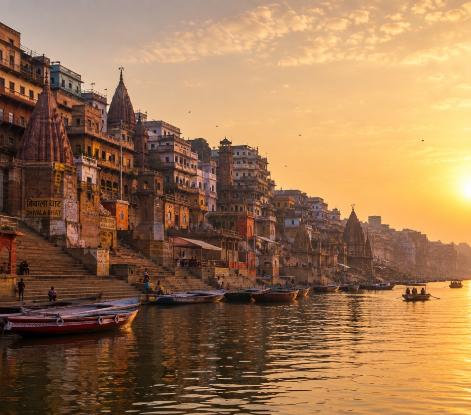 Sunrise over the ghats of Varanasi, with boats on the Ganges and temple spires along the riverbank